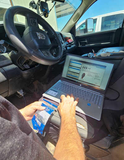Man looking through laptop for key car parts.